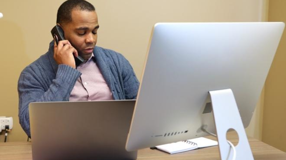 A4362 mitel-man-on-mitel-phone-at-desk-using-computer