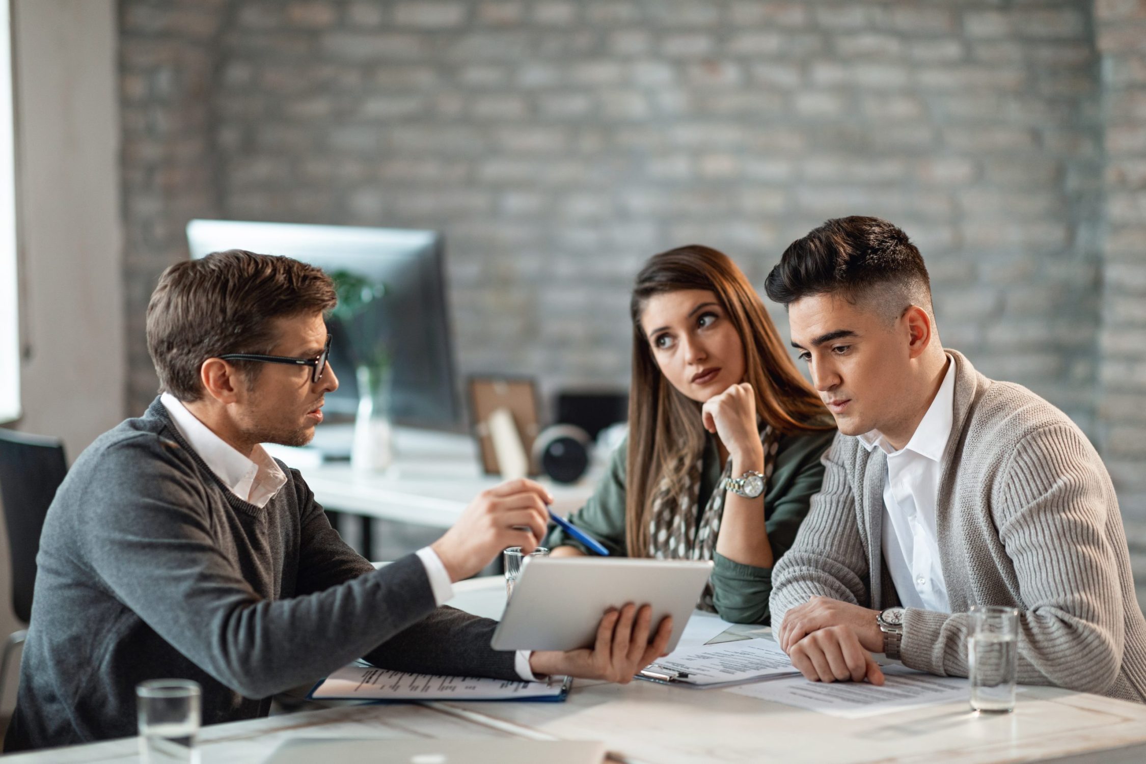 Financial advisor and young couple using touchpad on a meeting. Young couple using digital tablet with their insurance agent during consultations in the office.